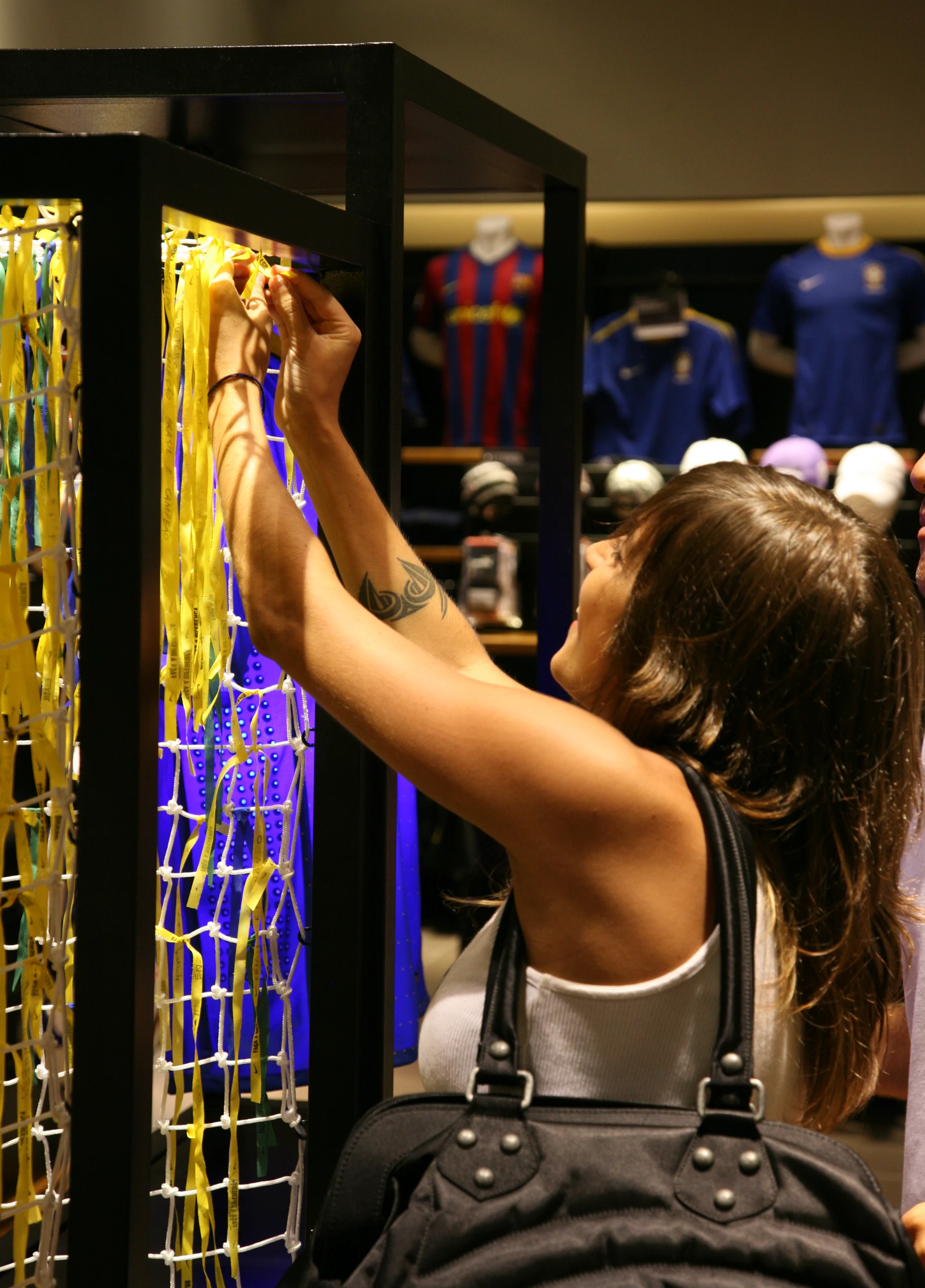 Participante amarra uma fita na rede da instalação Nike e CBF.