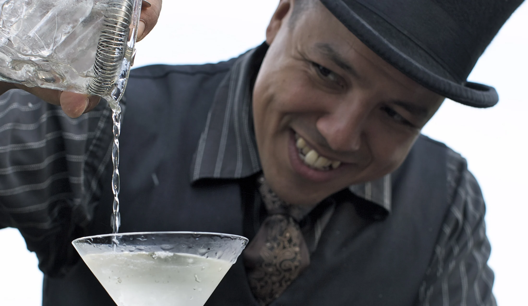 Bartender com cartola servindo um coquetel durante o evento.