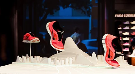 Detalhe frontal do expositor Nike Free com calçados vermelhos sobre uma representação branca do Rio de Janeiro.