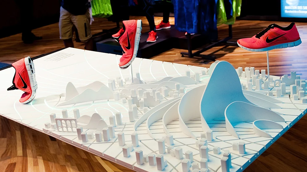 Expositor Nike Free com uma paisagem do Rio em miniatura, curvas brancas, Pão de Açúcar azul e calçados vermelhos.